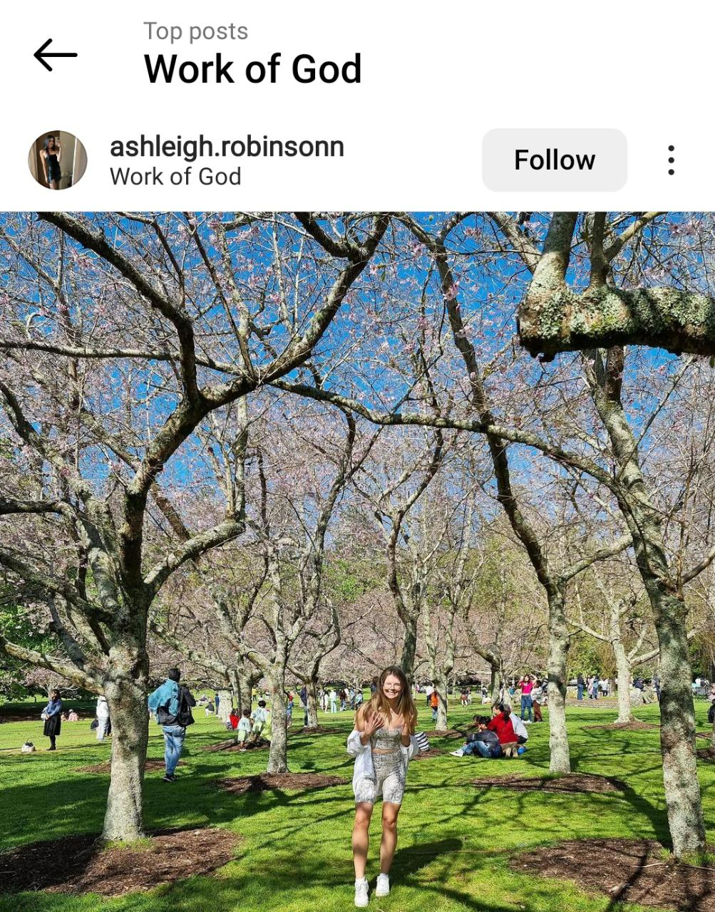 Instagram image of a woman standing beneath a group of budding trees.