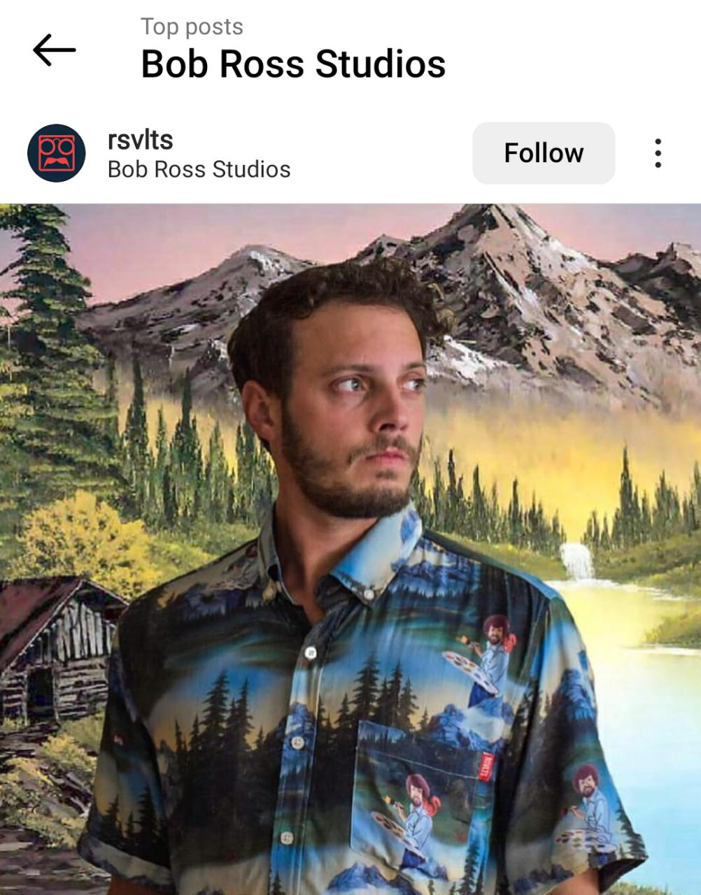 Instagram image of a man dressed in a Bob Ross print shirt in front of a Bob Ross style painting.