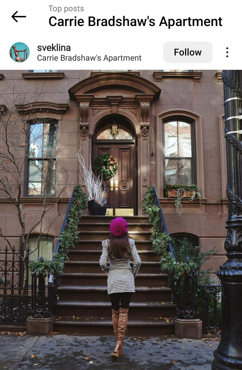 Instagram post of a woman standing in front of Carrie Bradshaw's brownstone apartment.